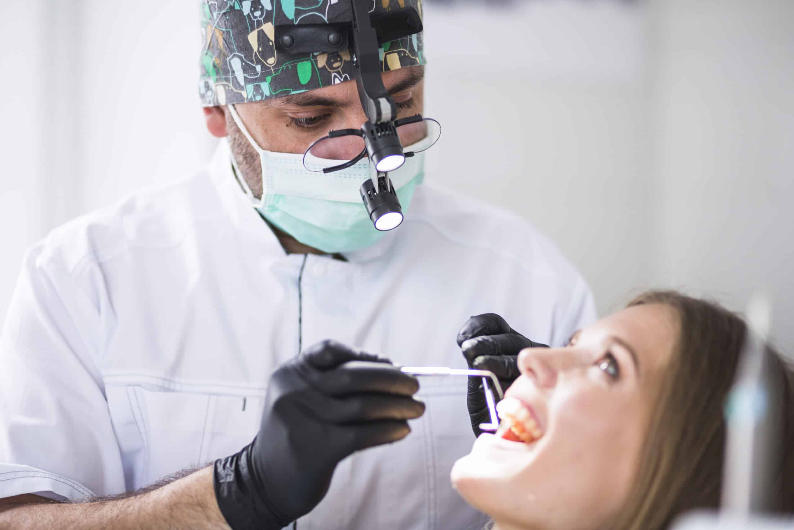 doctor checking female patient's teeth