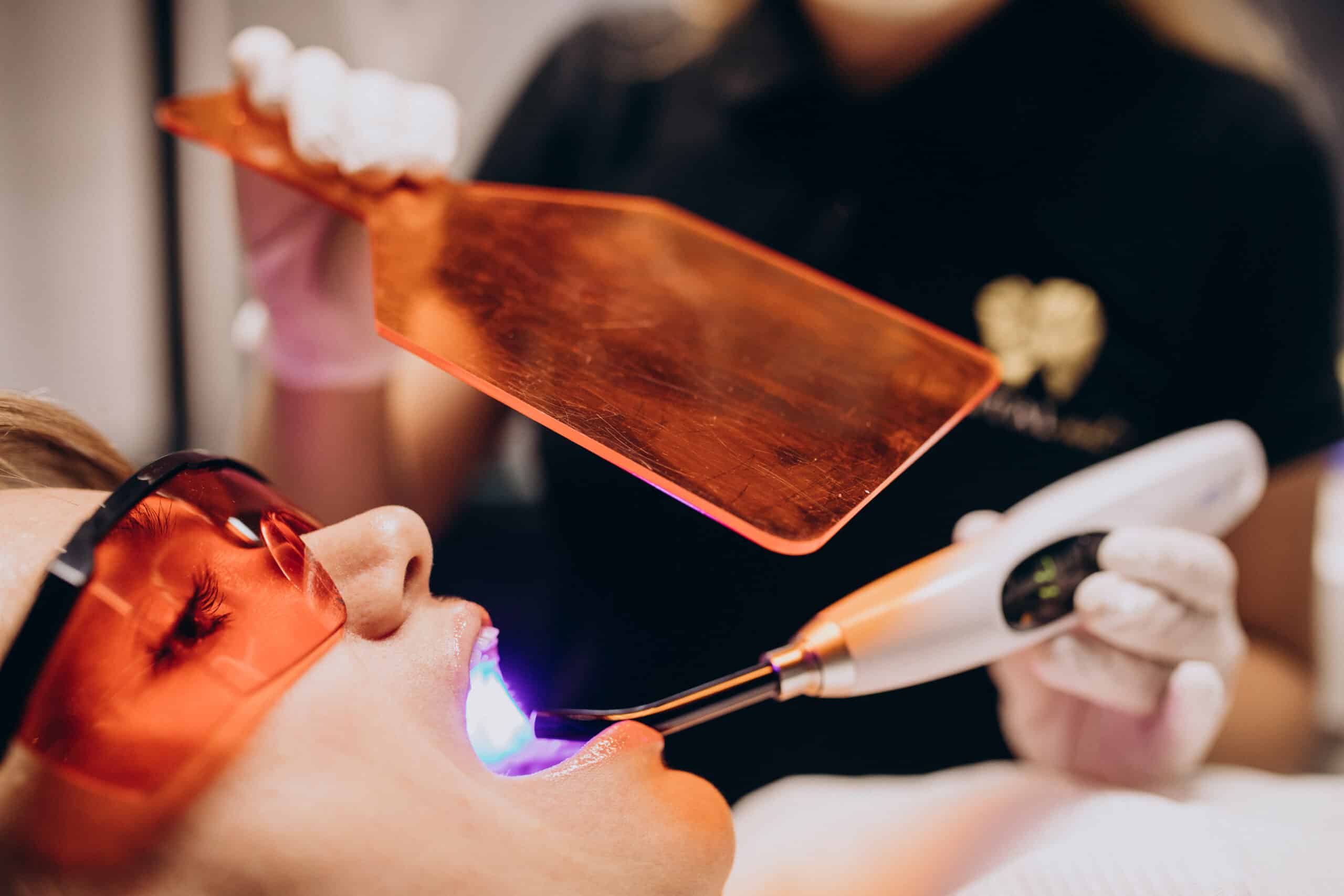 Dentist performing a dental procedure using blue light technology on a patient in Frisco, TX